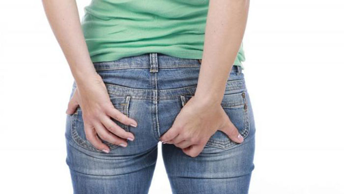 Người phụ nữ đưa tay ra sau lưng vì ngứa rát vùng hậu môn
